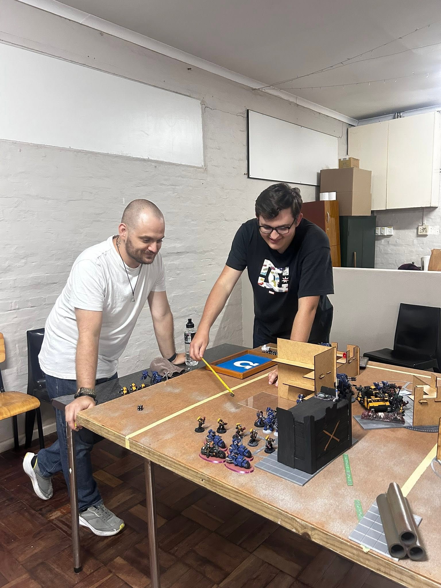Two members playing Blood Bowl at a kitchen table